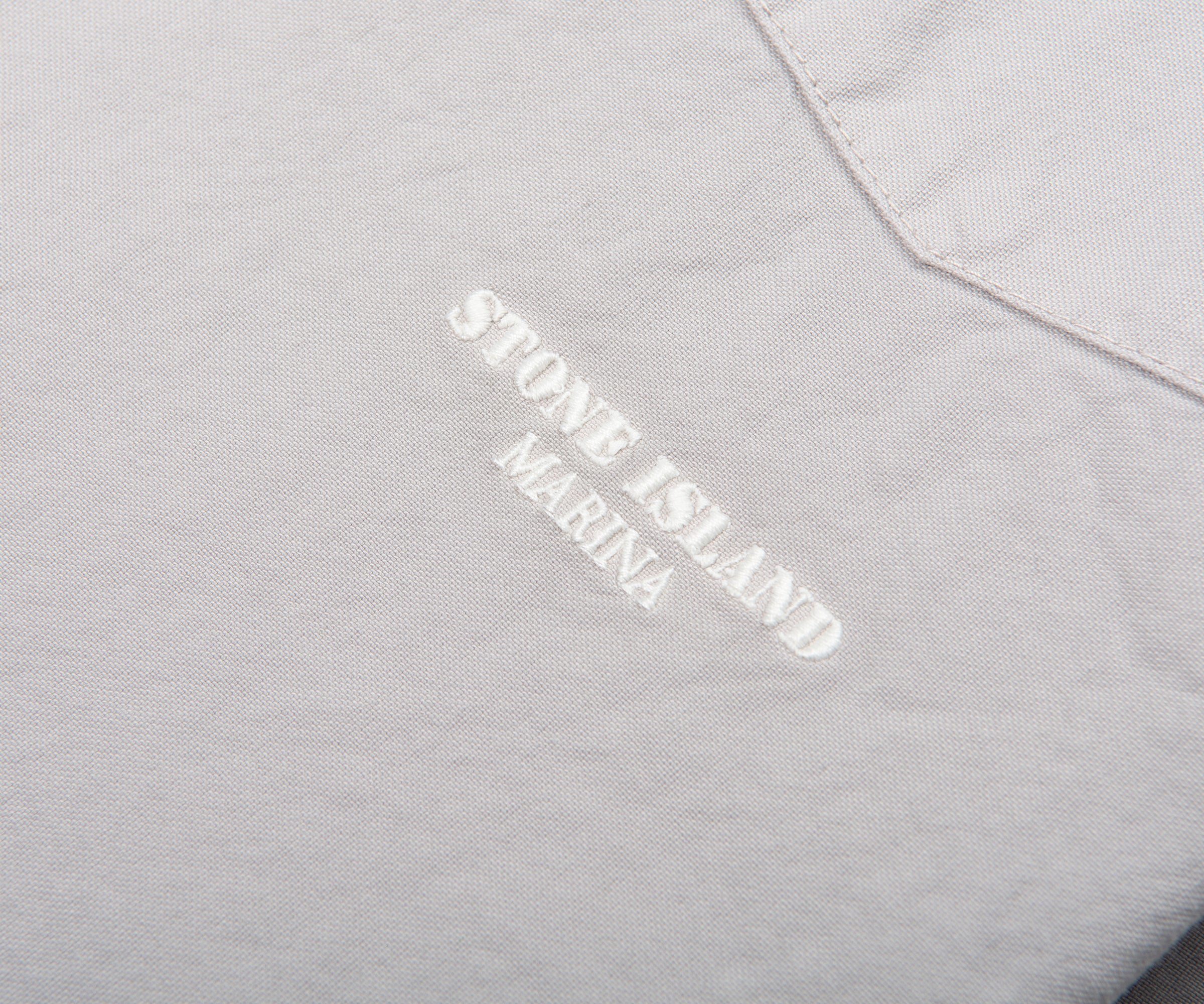 Close-up of Stone Island Marina logo on a gray fabric background