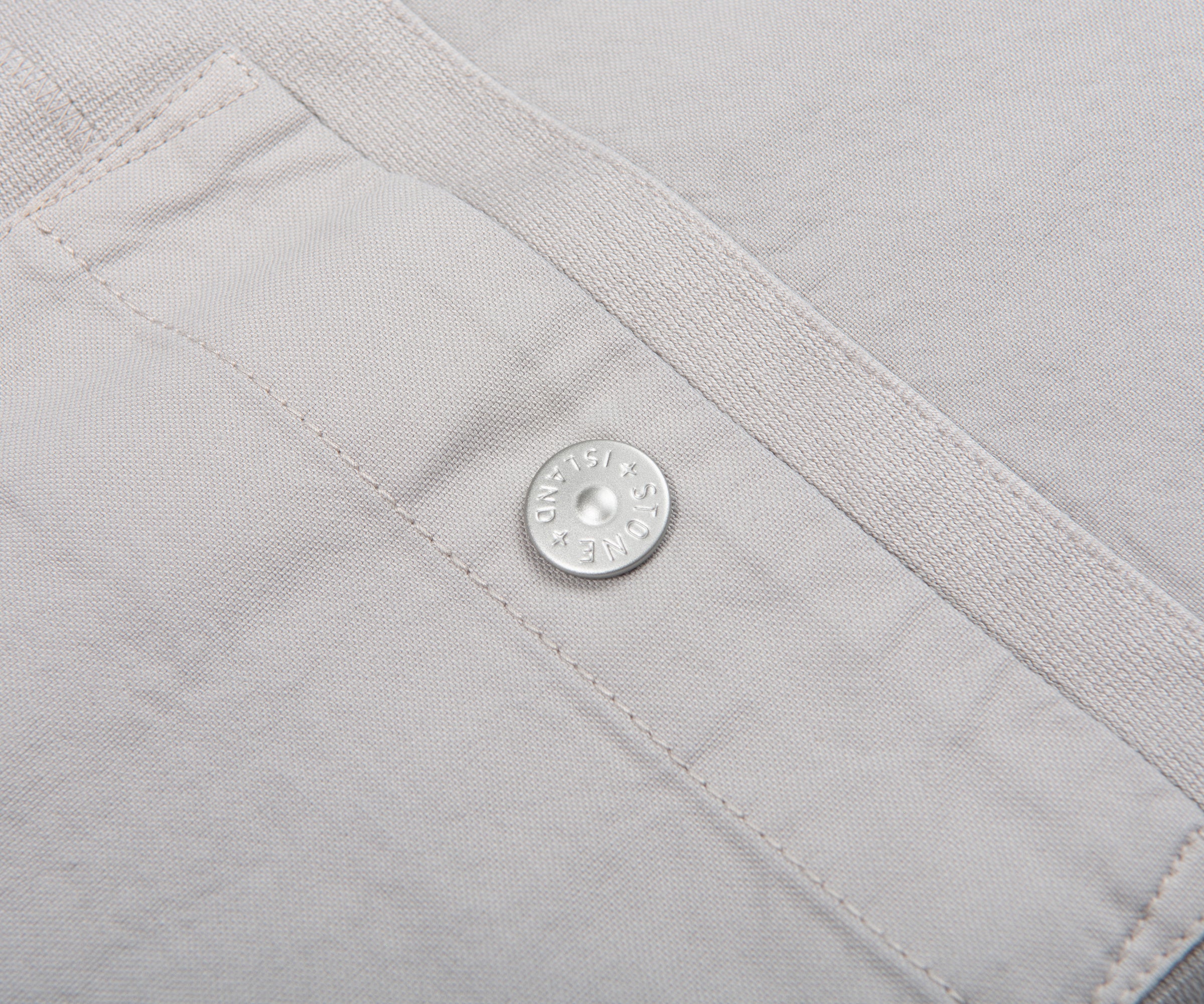 Close-up of a gray fabric with a brand logo on a button