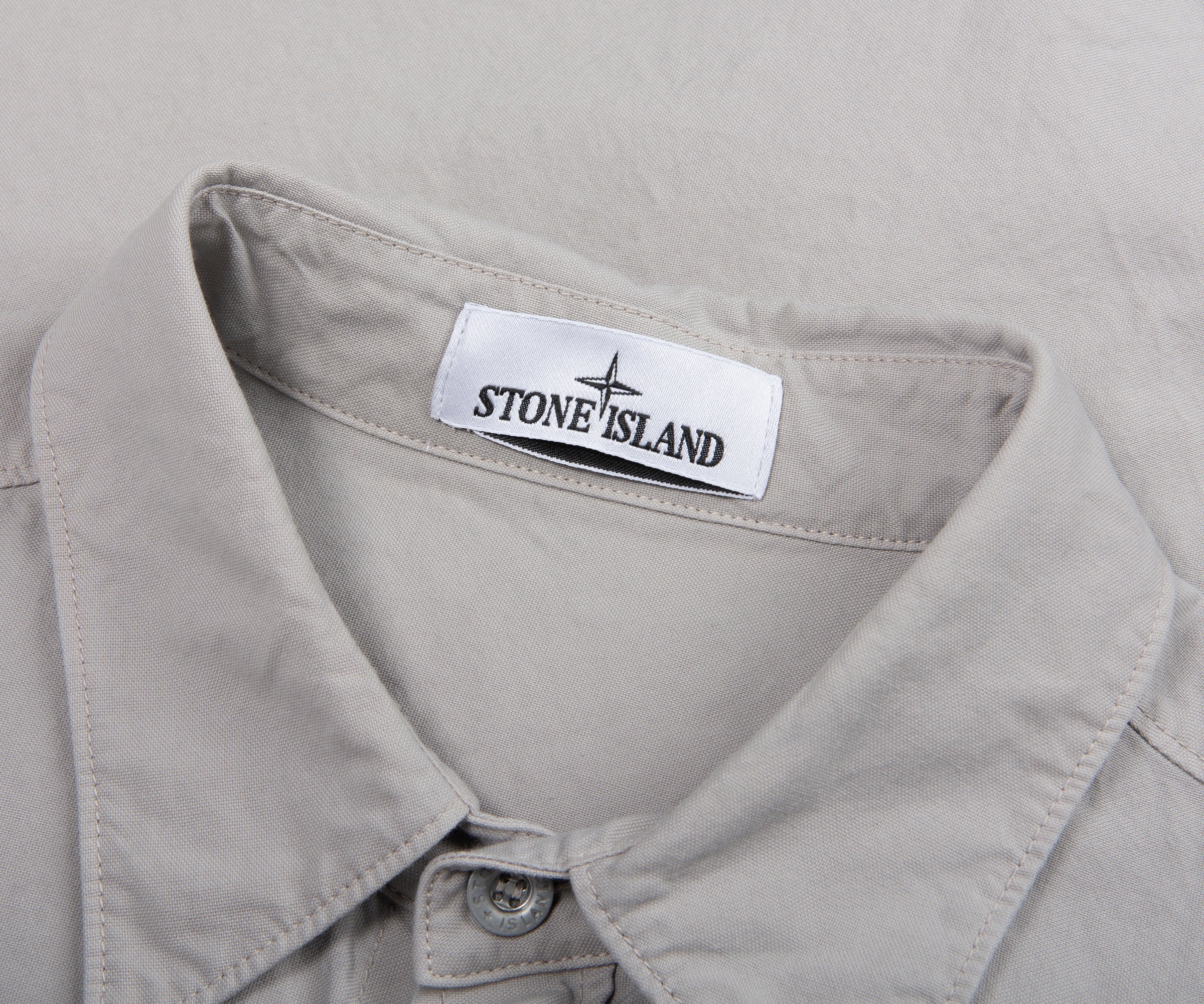 Close-up of a Stone Island label on a light gray shirt collar.