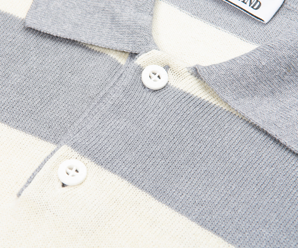 Close-up of a gray and white striped sweater with buttons, brand label visible.