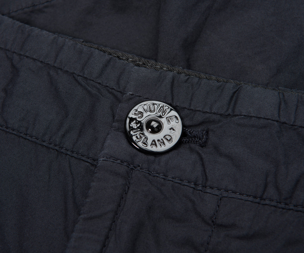 Close-up of a button on a dark fabric with 'New Zealand' branding.
