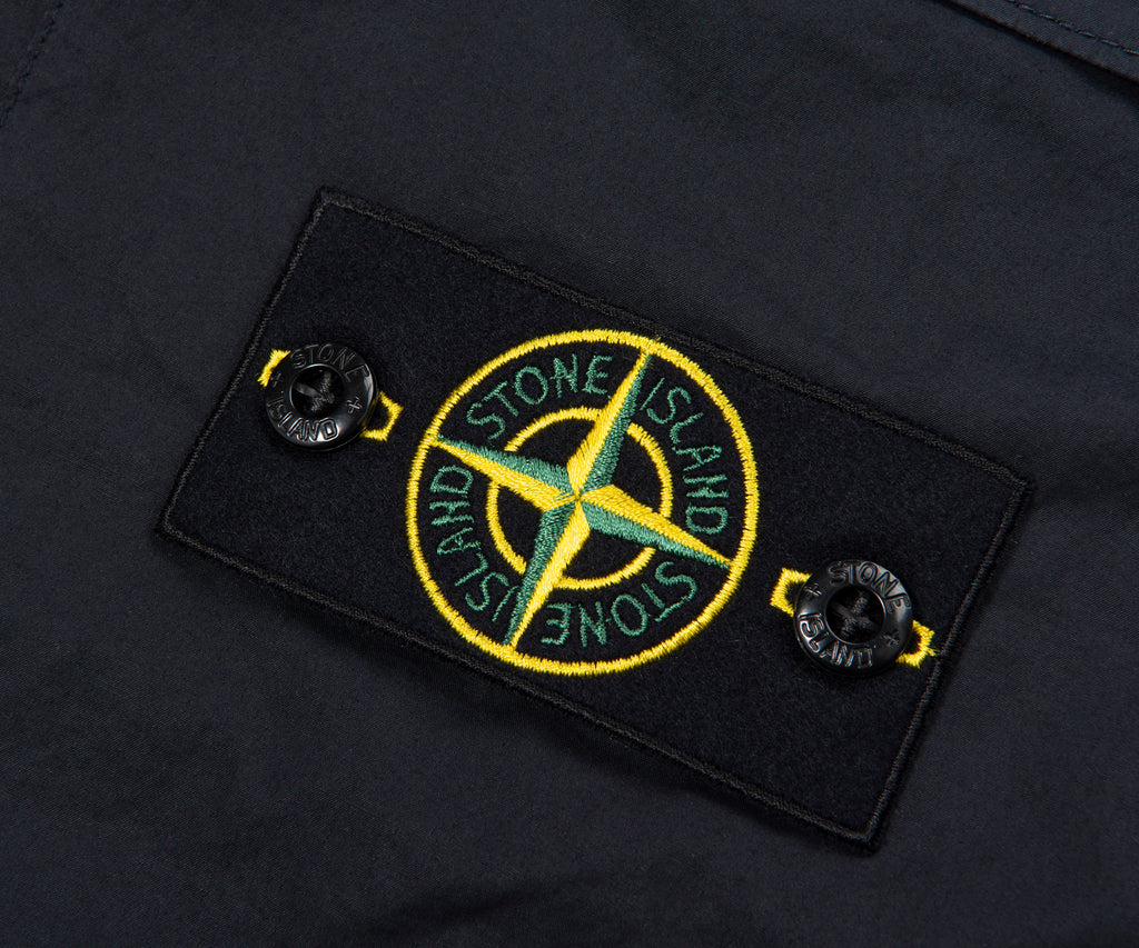 Close-up of a Stone Island logo patch on a dark fabric background