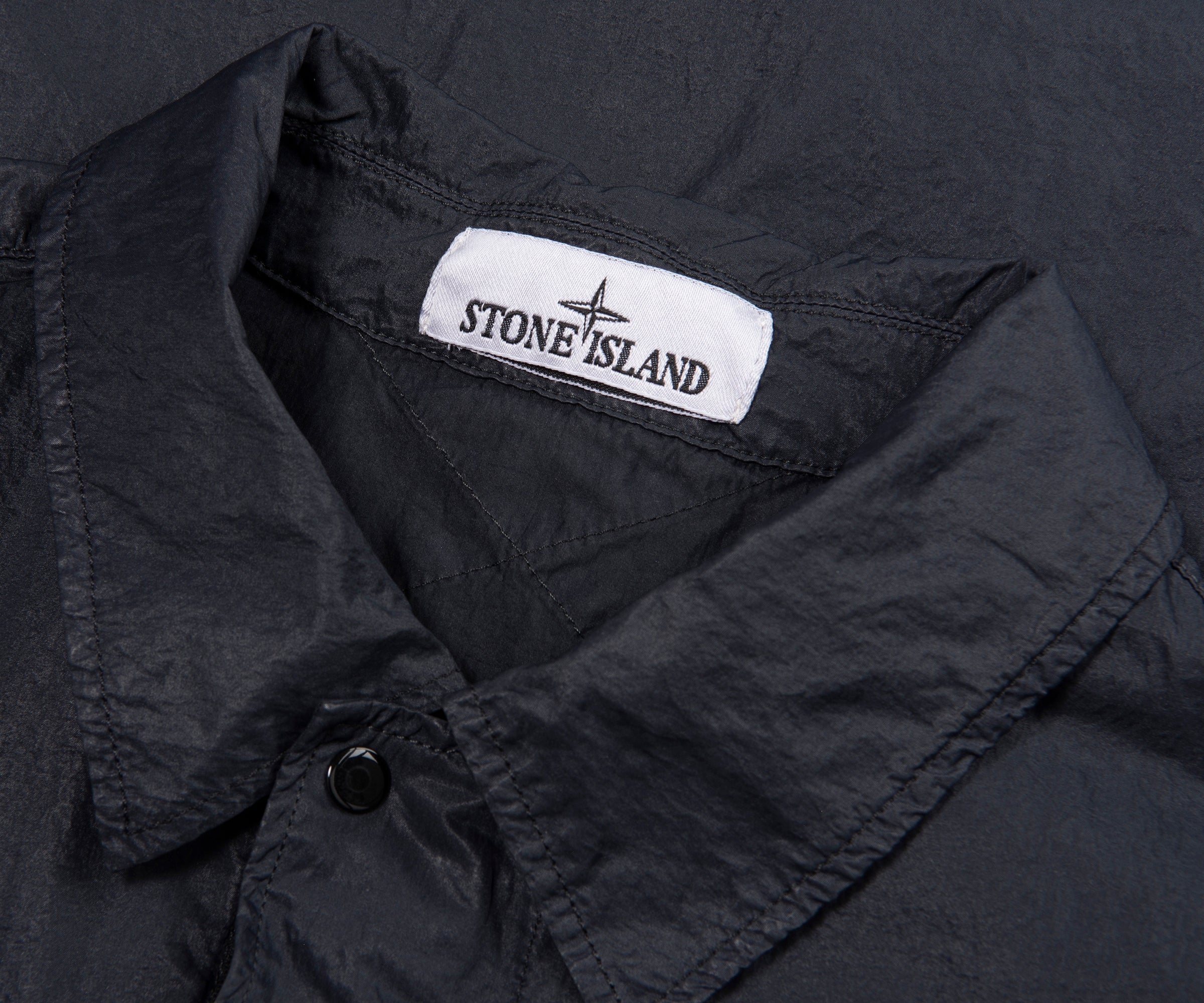 Close-up of a black jacket with Stone Island logo on the collar.