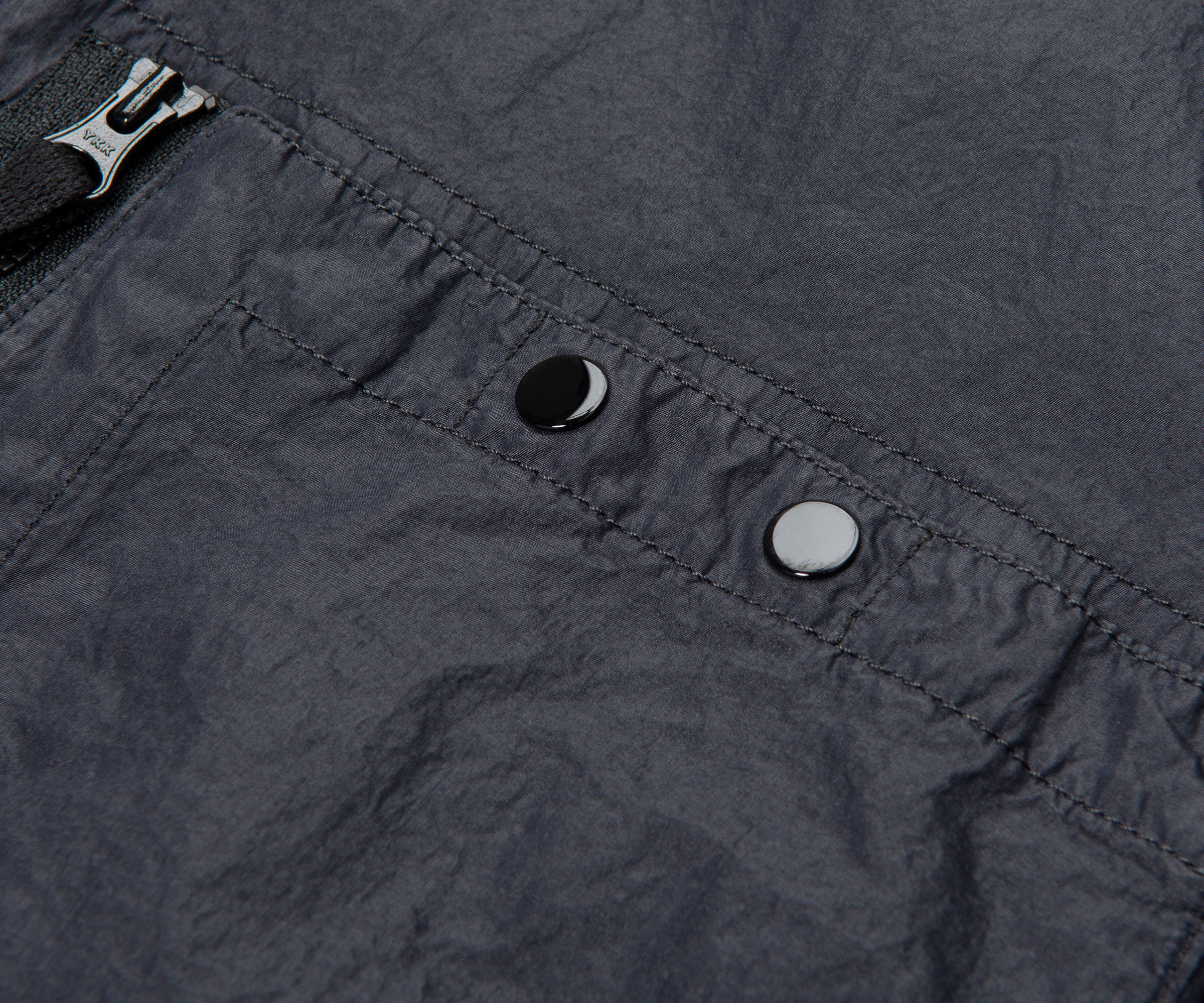 Close-up of a dark gray fabric with a zipper and buttons.