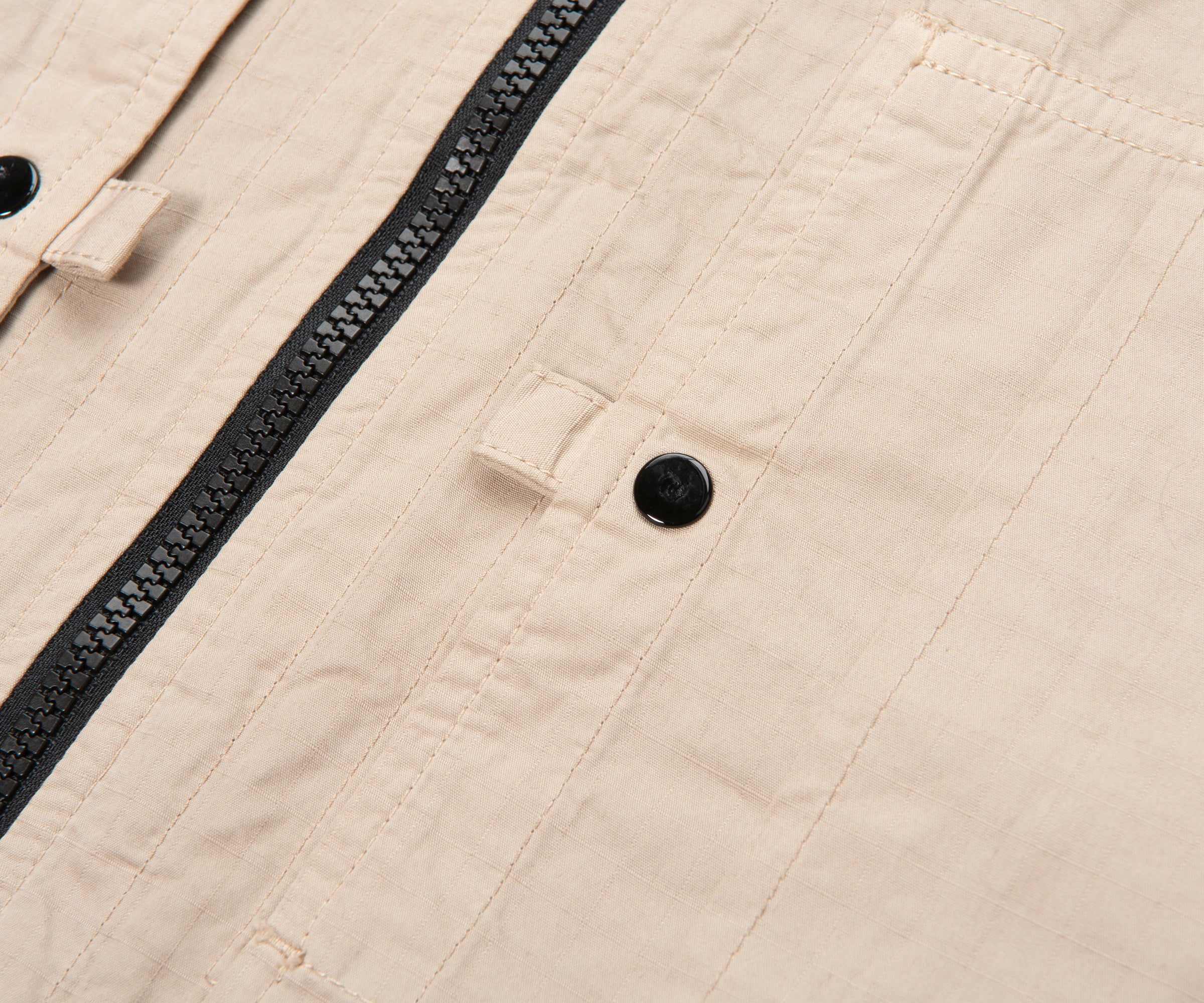 Close-up of beige fabric with a zipper and button