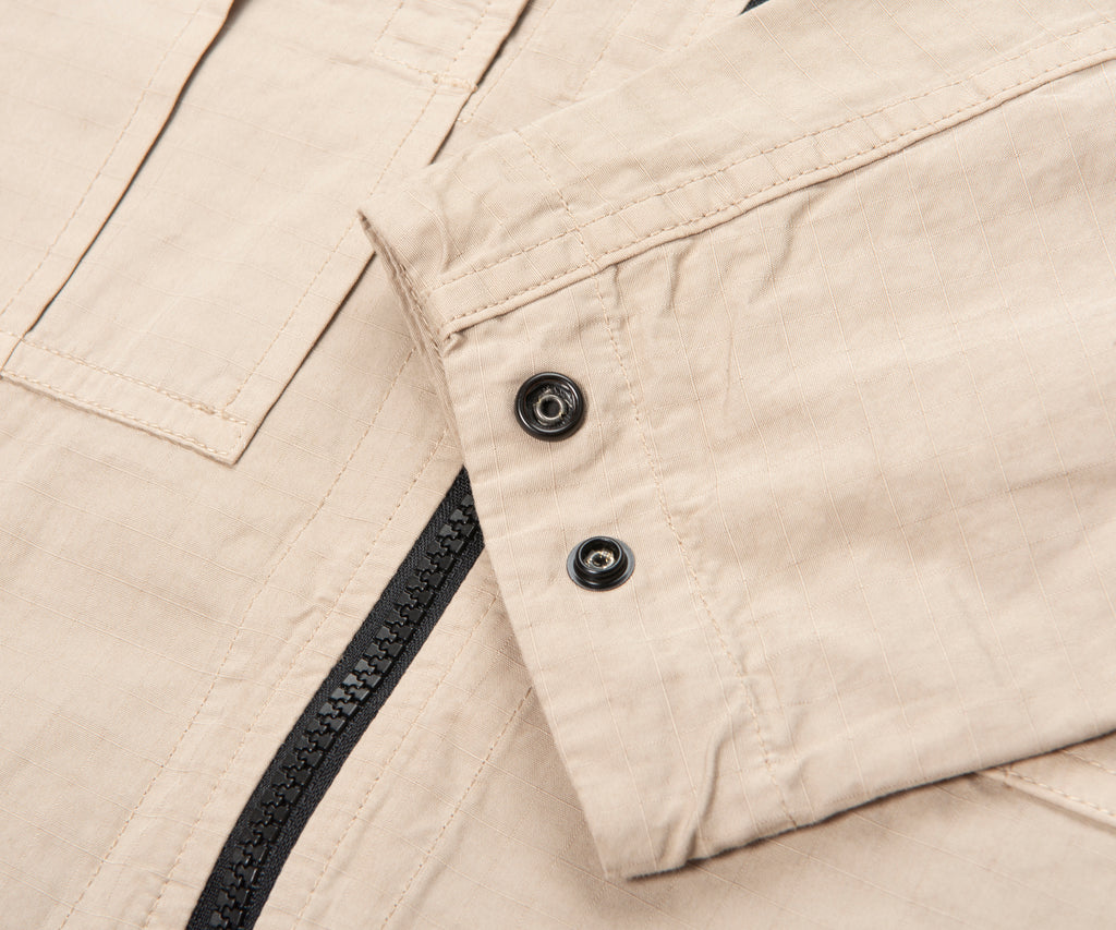 Close-up of beige fabric with a zipper and buttons