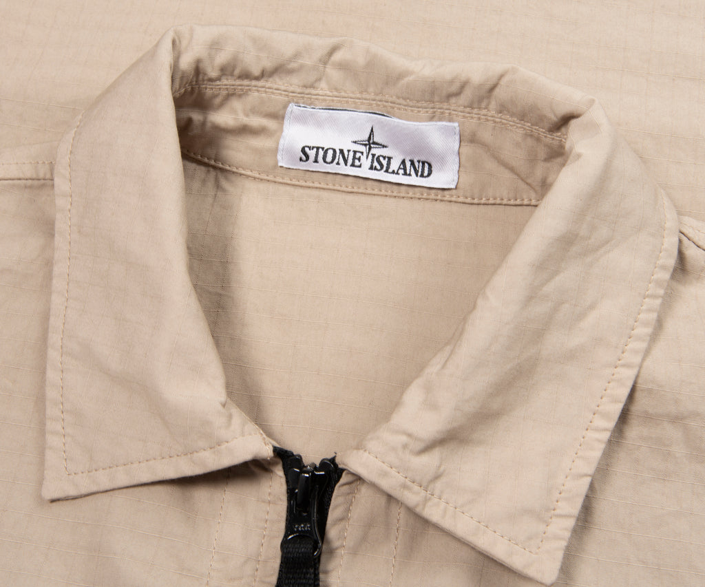 Close-up of a beige jacket with a Stone Island label.