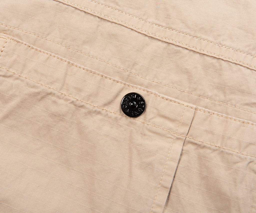 Close-up of beige fabric with a black button
