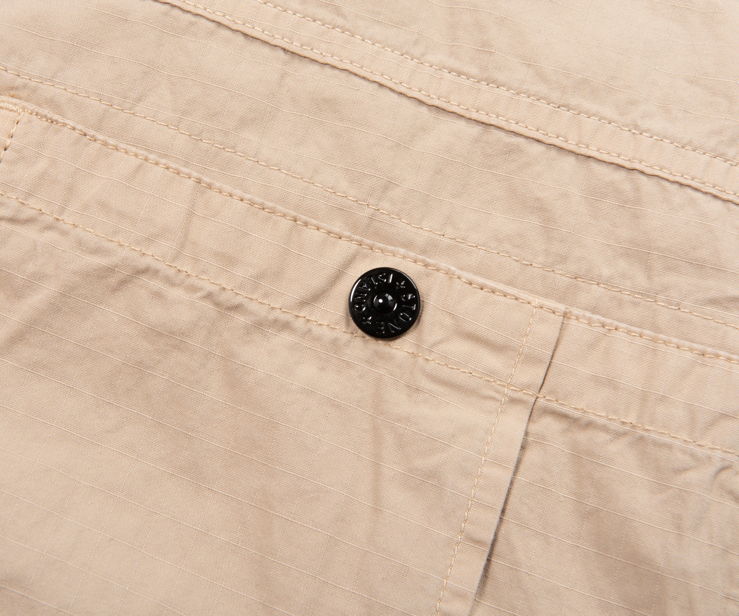 Close-up of beige fabric with a black button