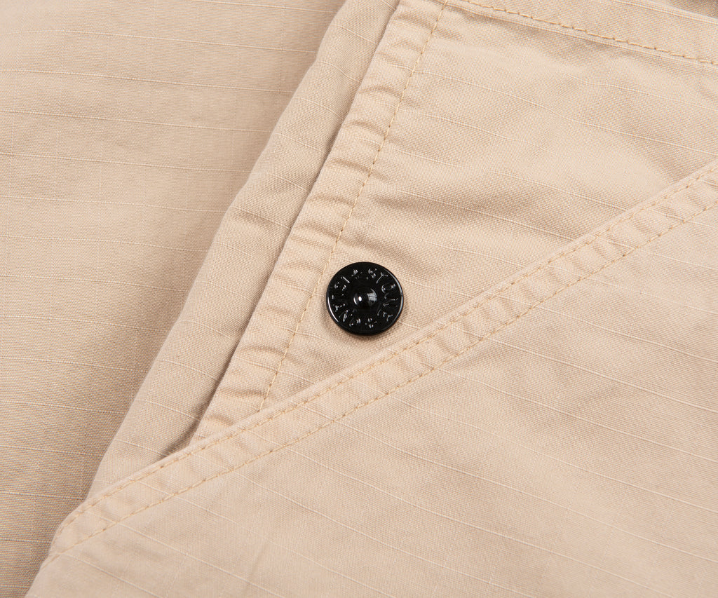 Close-up of beige fabric with a button on a beige background