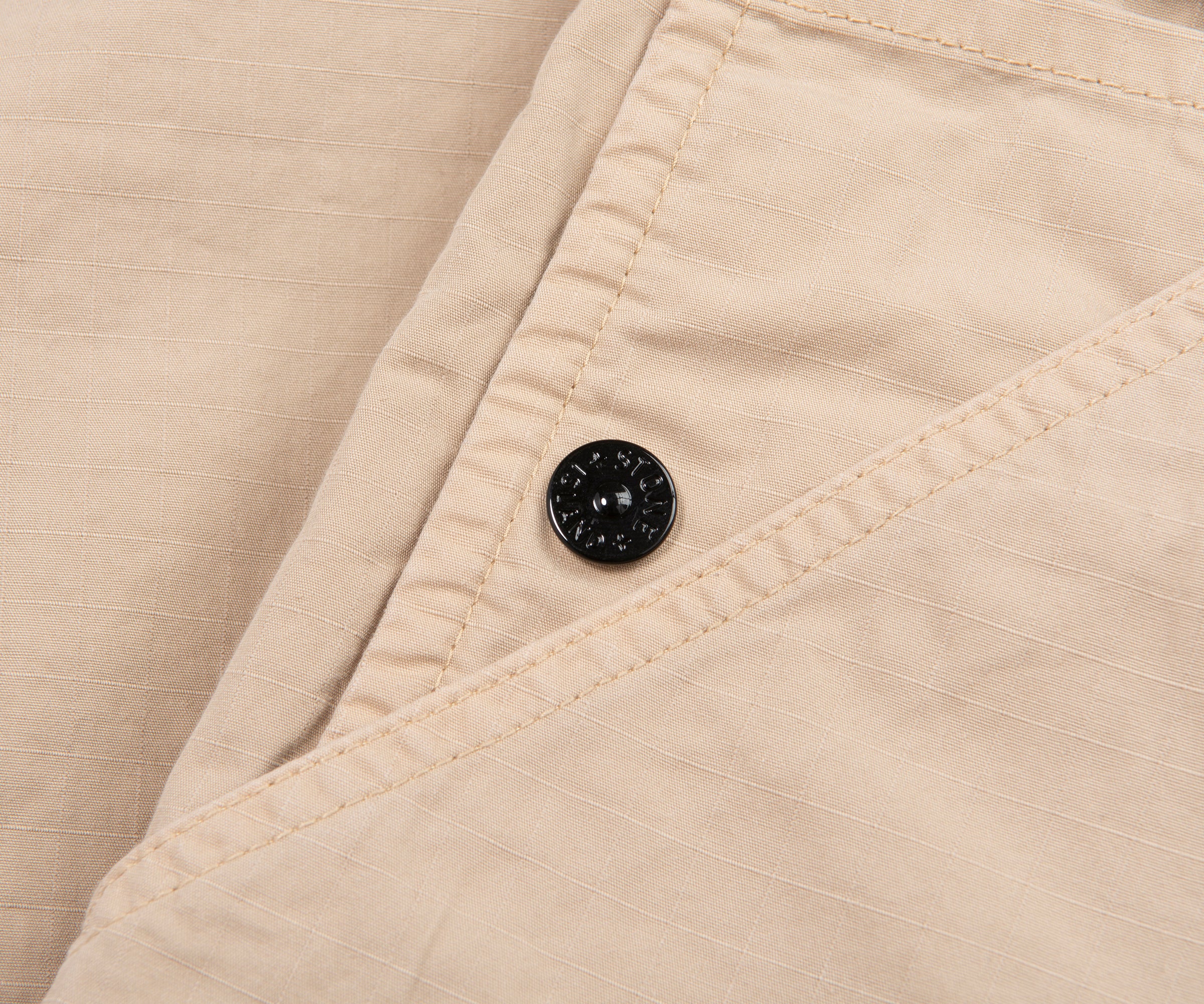 Close-up of beige fabric with a button on a beige background