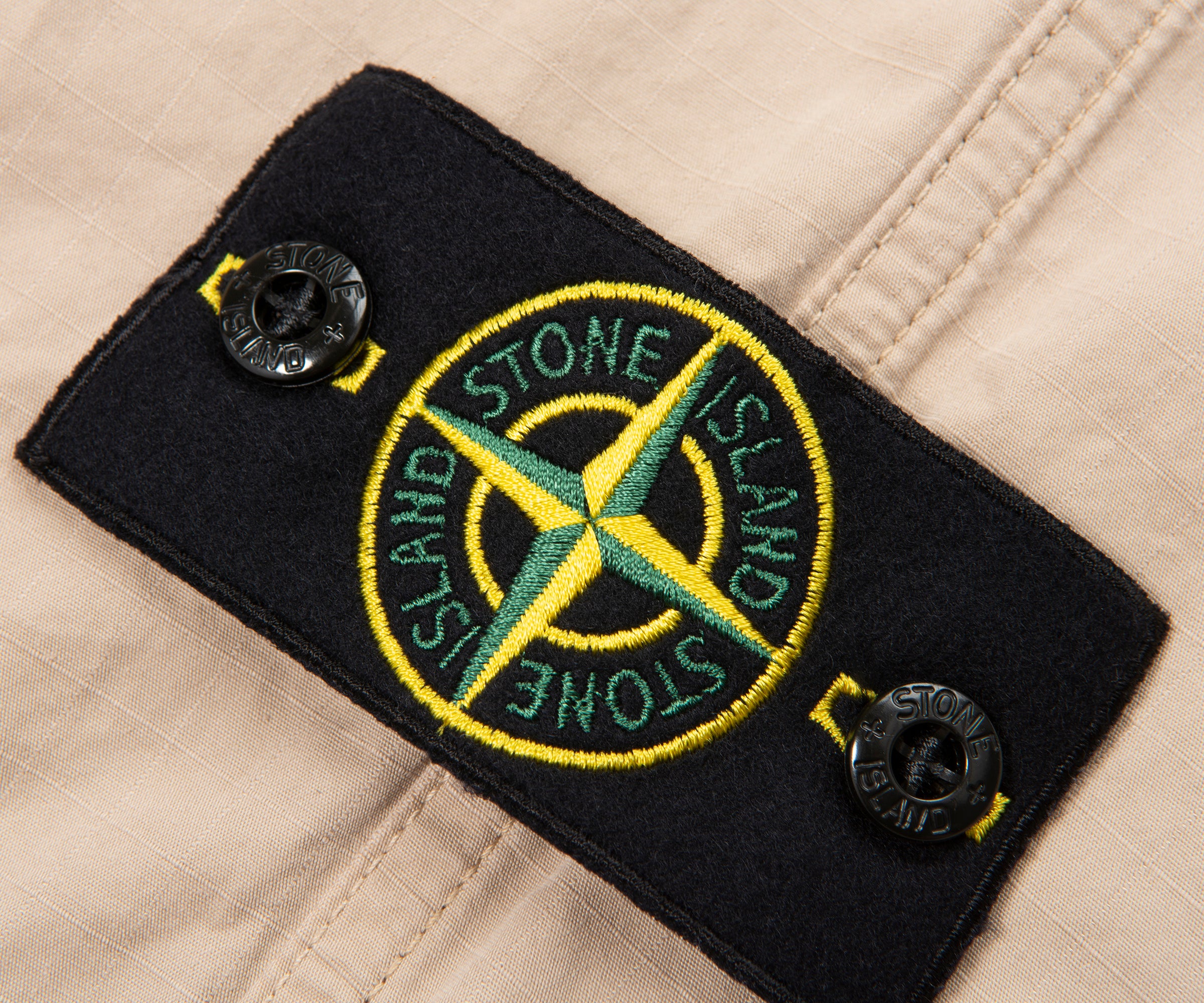 Close-up of Stone Island patch on a beige background