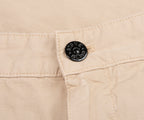 Close-up of beige fabric with a button featuring a logo.