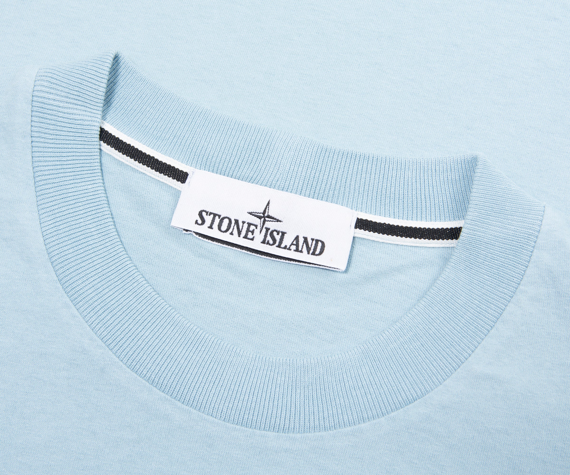 Close-up of a light blue sweater with a Stone Island label.
