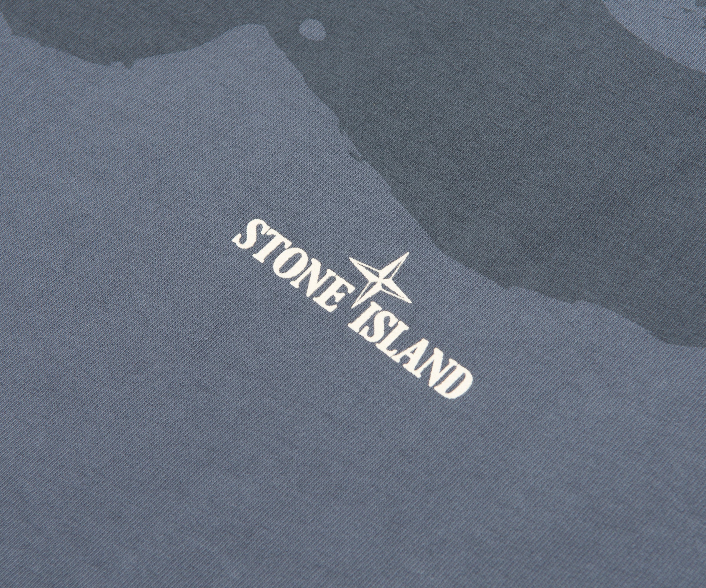 Close-up of Stone Island logo on a textured fabric background