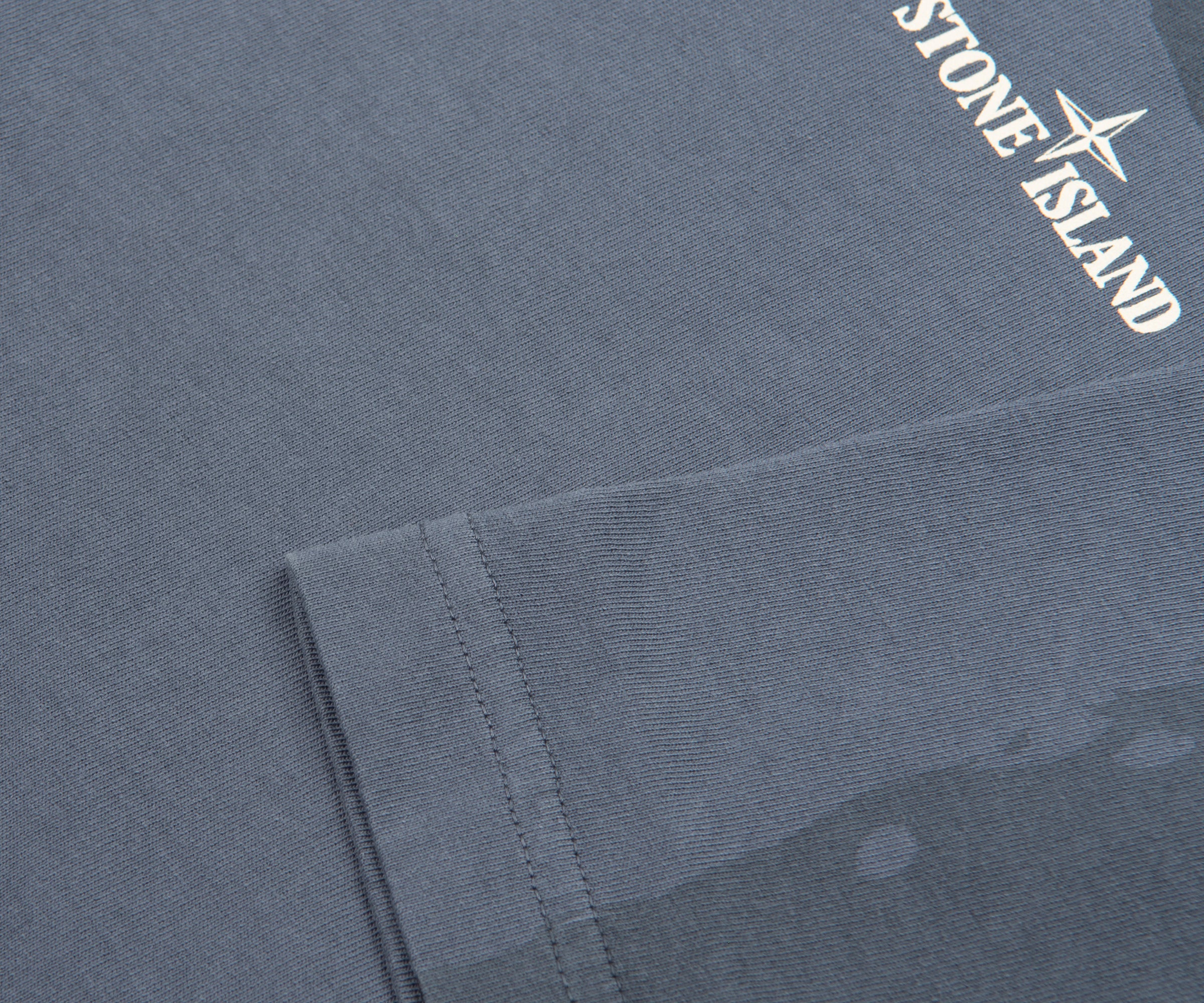 Close-up of a gray fabric with Stone Island logo on a gray background