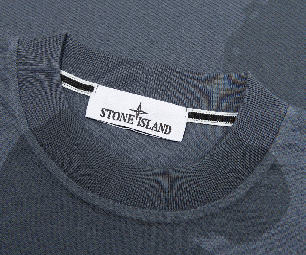 Close-up of a gray sweater with a Stone Island label on a matching gray background