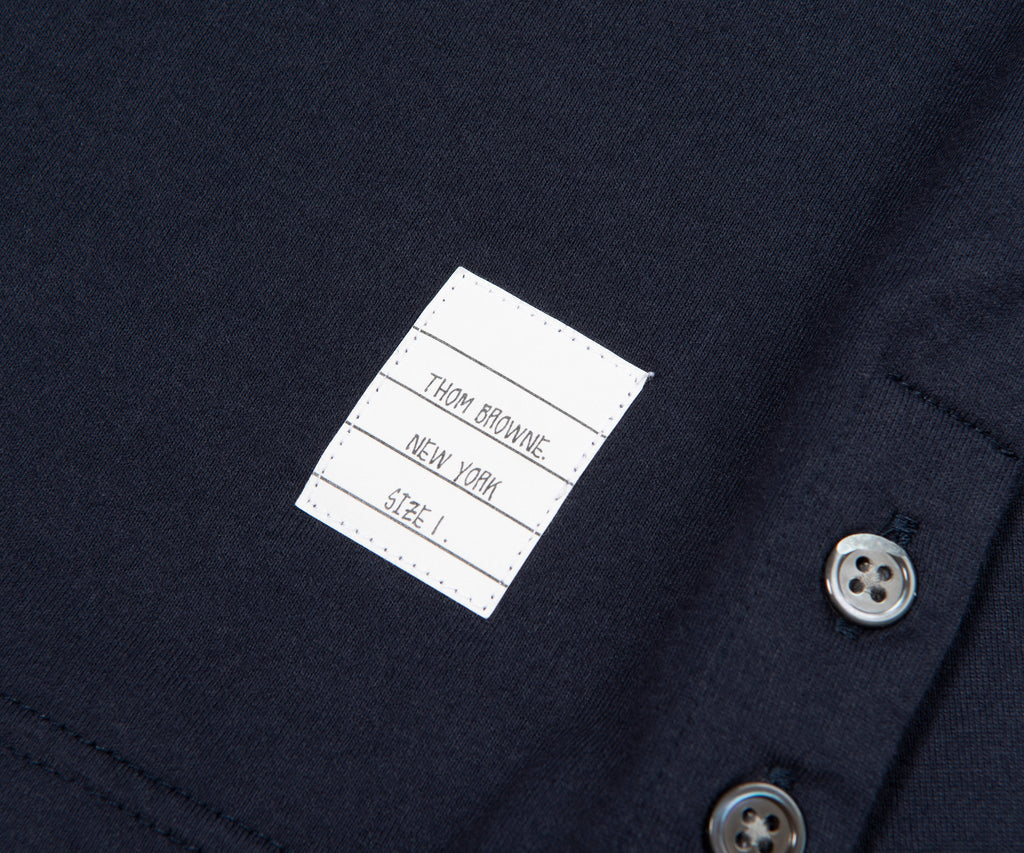 Close-up of a label on a dark fabric with buttons, featuring 'Tom Browning New York'.