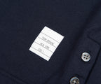 Close-up of a label on a dark fabric with buttons, featuring 'Tom Browning New York'.