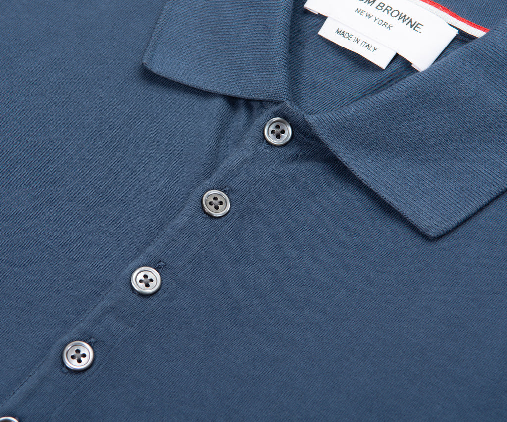 Close-up of a blue polo shirt with buttons and a brand tag.
