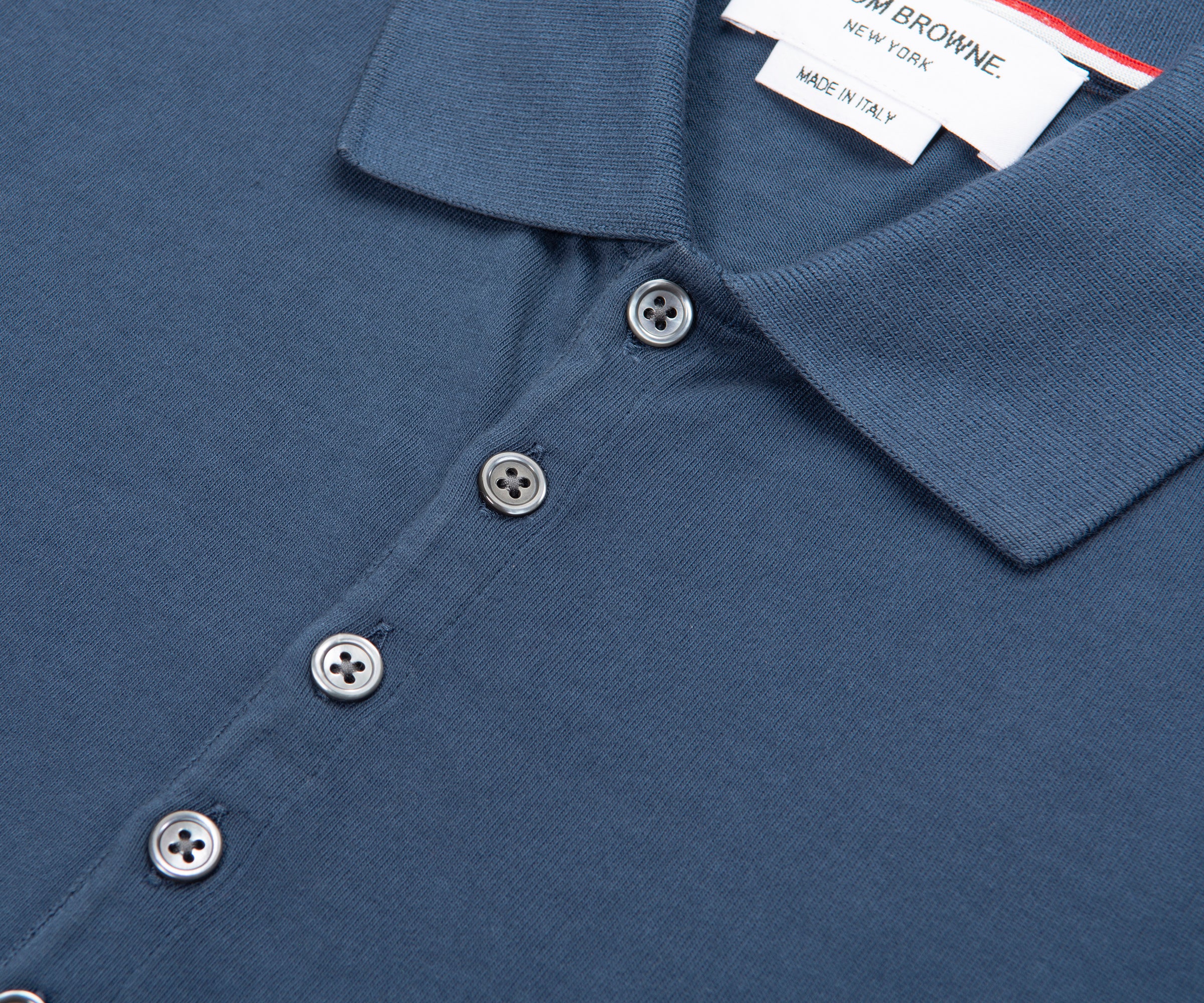 Close-up of a blue polo shirt with buttons and a brand tag.