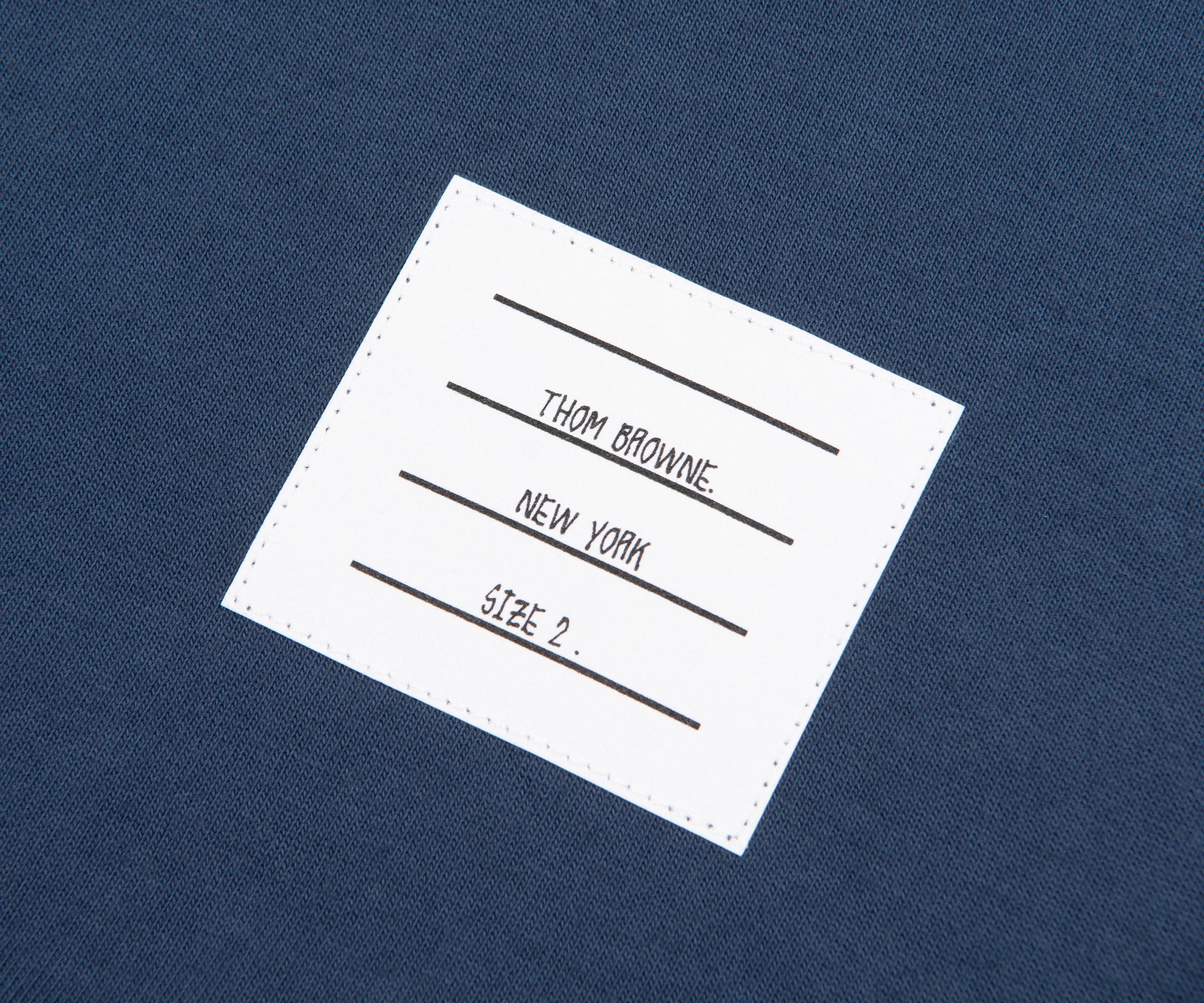 Thom Browne label on a blue fabric background