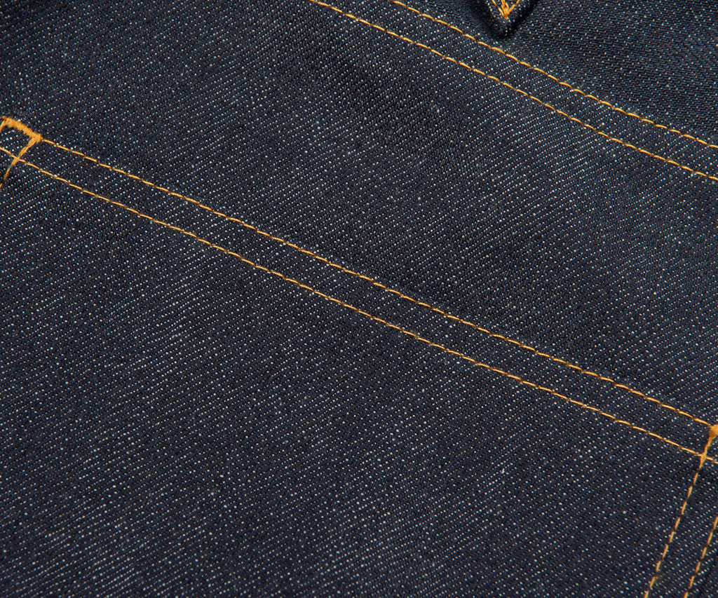 Close-up of dark blue denim fabric with visible stitching