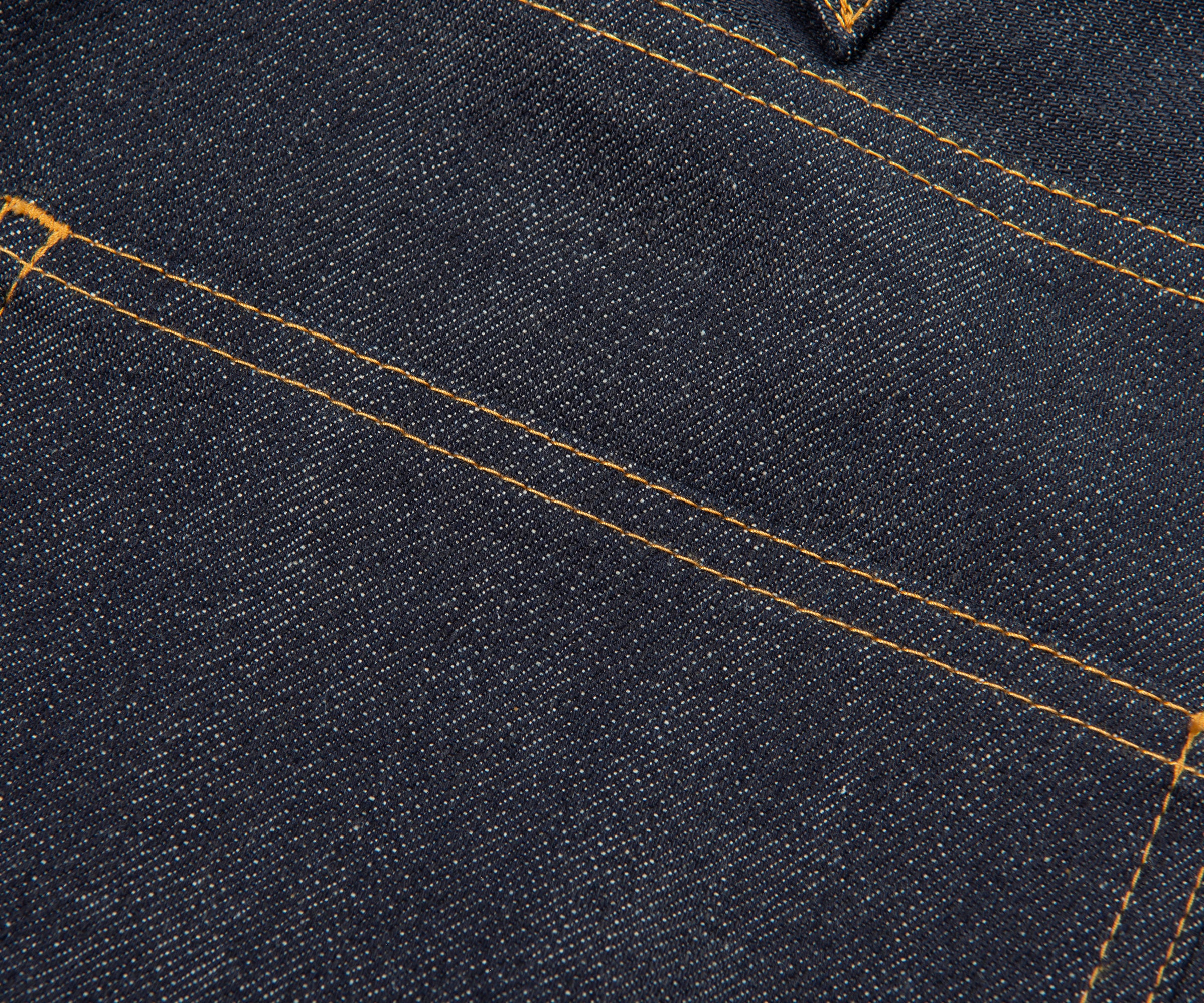 Close-up of dark blue denim fabric with visible stitching