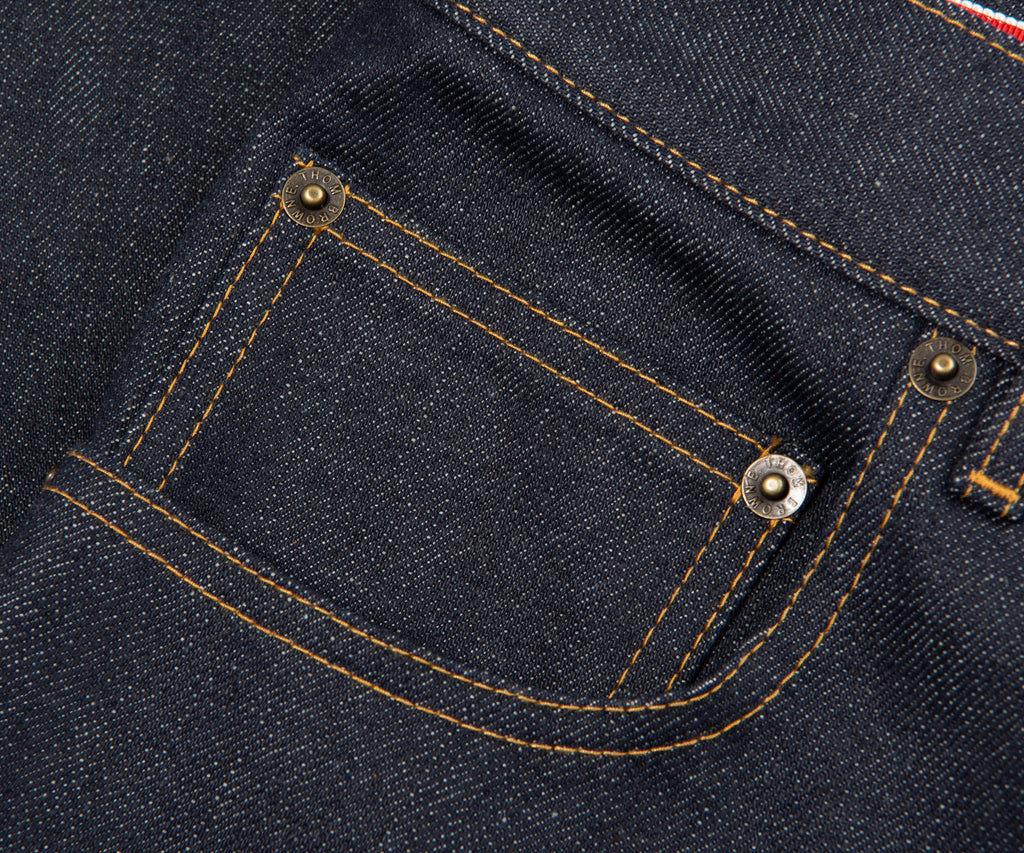 Close-up of a pocket on a dark blue denim fabric with stitching details.