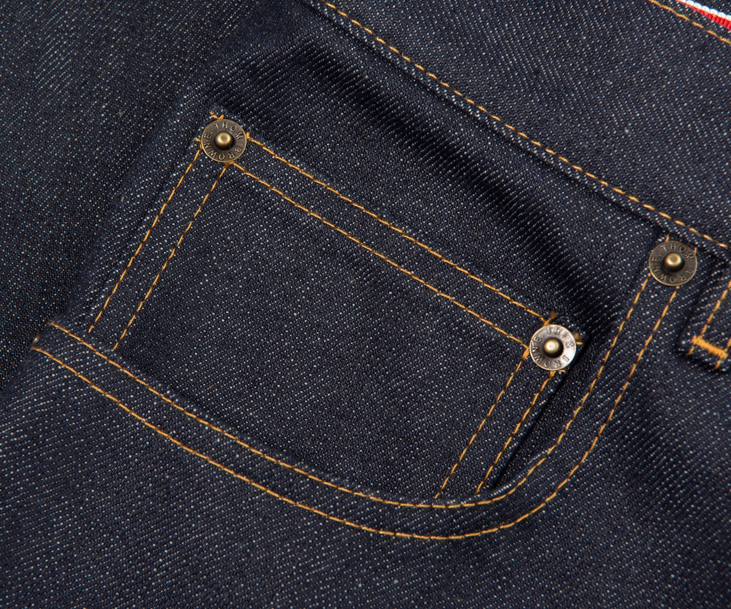 Close-up of a pocket on a dark blue denim fabric with stitching details.