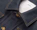 Close-up of a dark denim jacket with a button and striped lining.