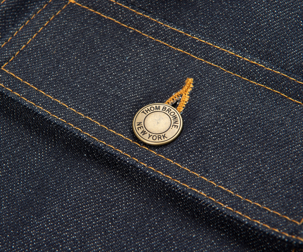Close-up of a denim fabric with a brand label on a dark blue background