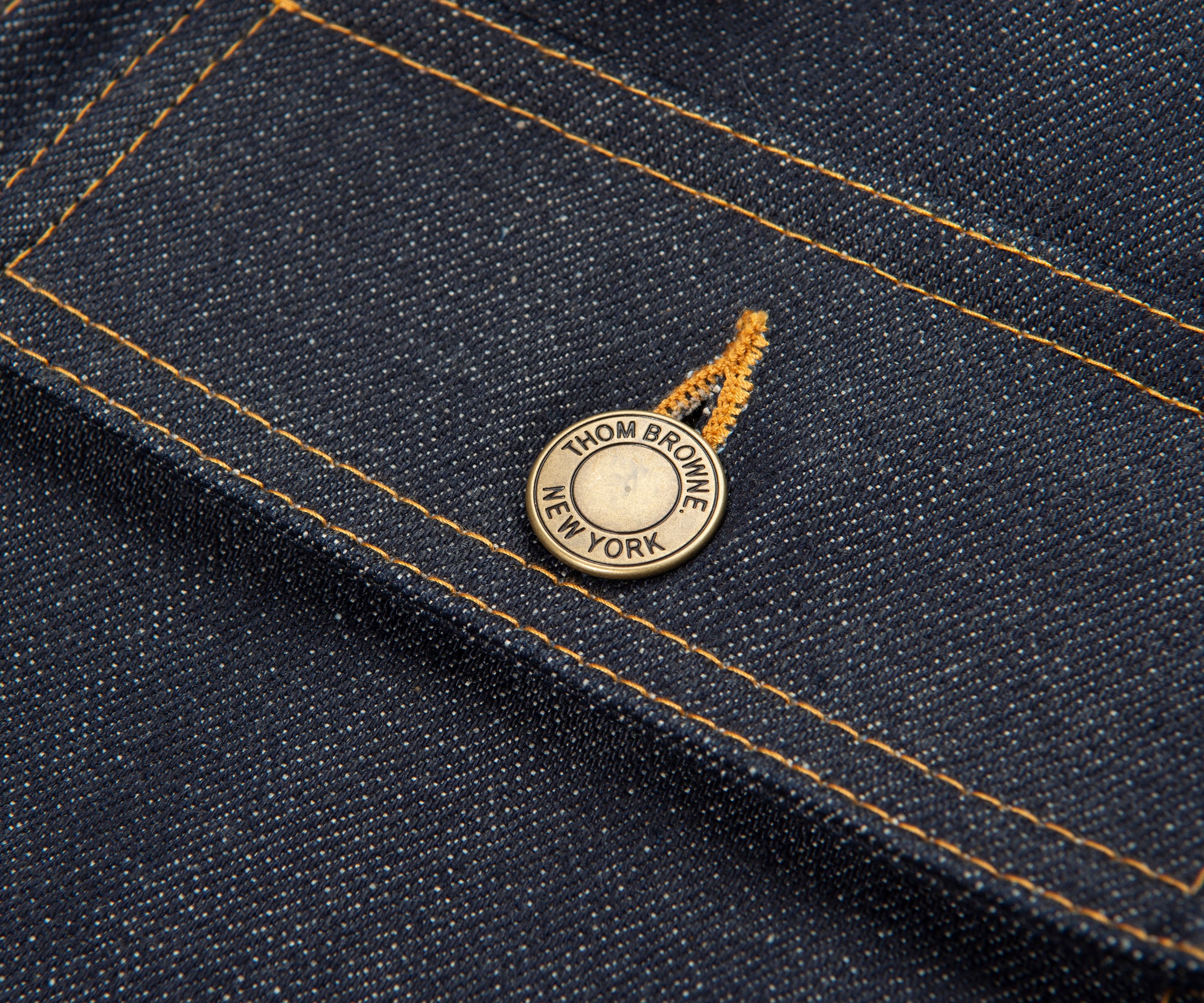 Close-up of a denim fabric with a brand label on a dark blue background