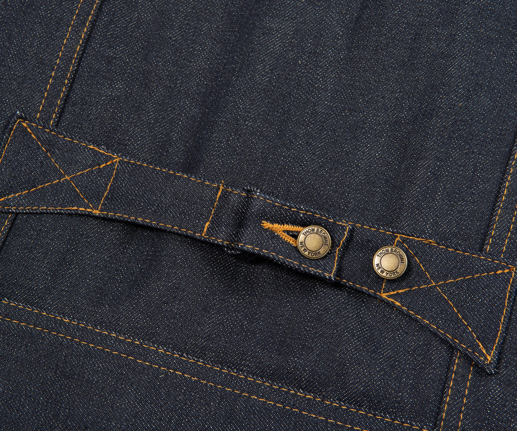Close-up of a button on a dark blue denim fabric with stitching details.