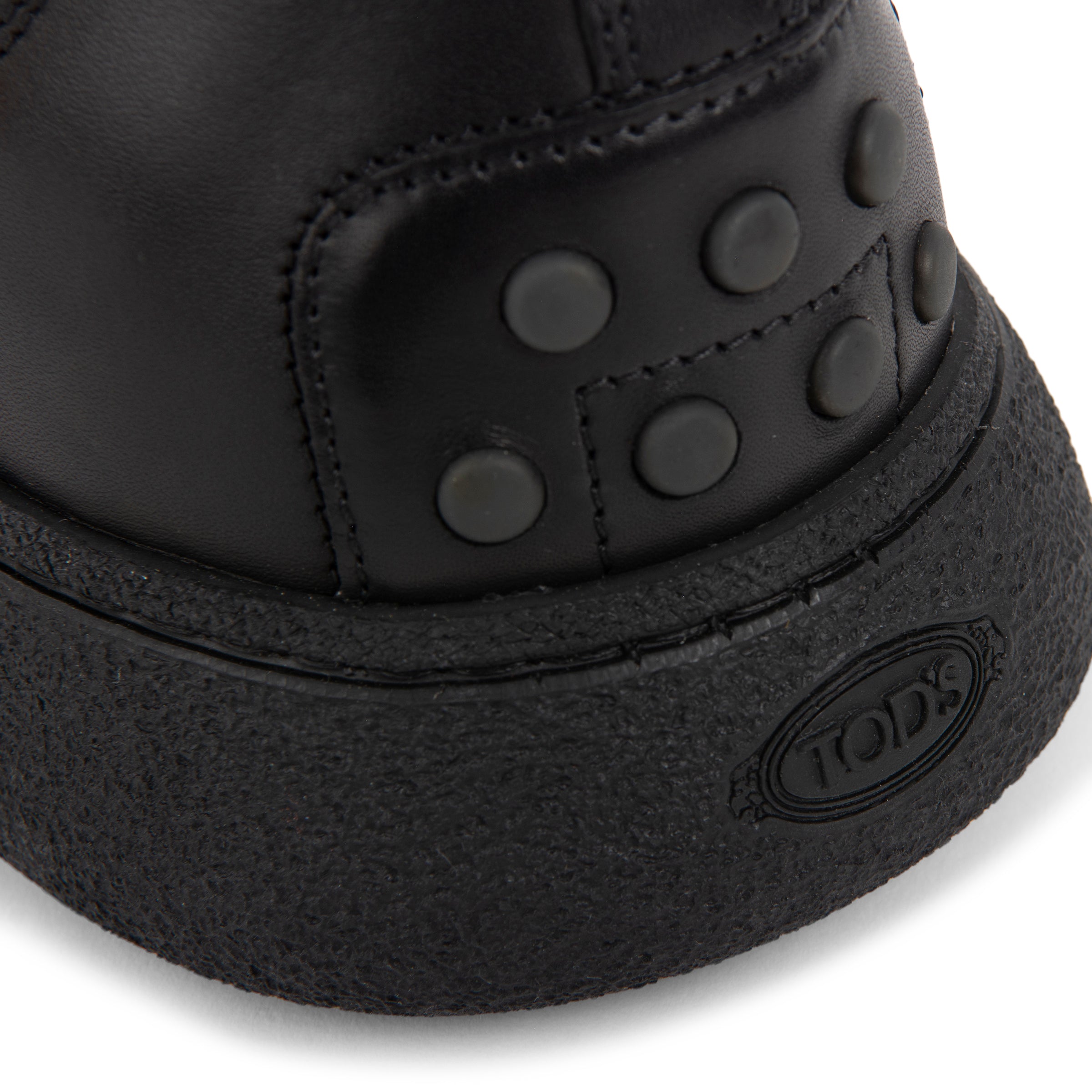 Close-up of a black boot with textured sole and visible brand logo on a white background