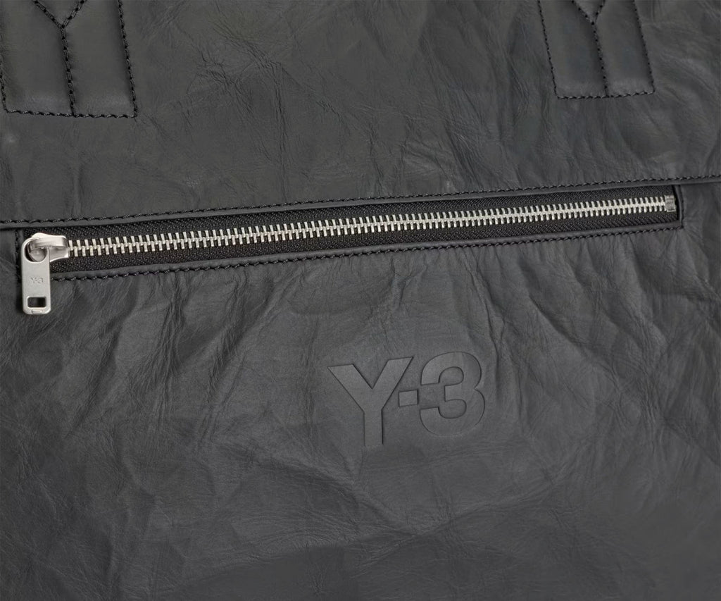 Close-up of a dark gray jacket with a zipper and Y-3 logo.