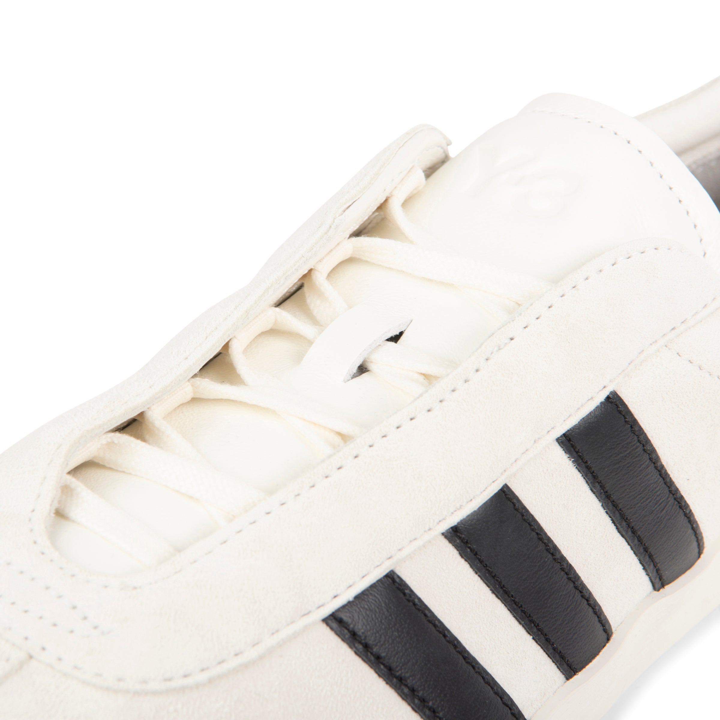 Close-up of a white sneaker with black stripes on a white background