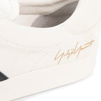 Close-up of a white sneaker with a gold logo on a white background